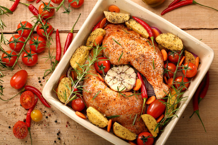 Chicken legs with vegetables and herbs ready for roastingの写真素材