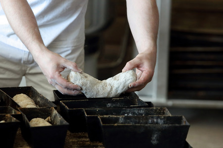 The baker puts bread dough to mold
