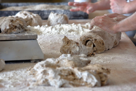 Baker kneading dough for bread in a bakery