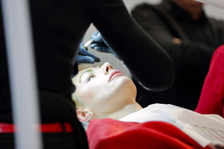 POZNAN, POLAND - MAY 07. 2016: Manicurist master painting eyebrow at The Look Beauty Vision Poznan 2016 on May 07 in Poznan, Poland.のeditorial素材