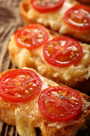 Grilled toast with cheese and tomatoes on old wooden backgroundの写真素材
