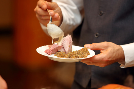 Waiter serves portions of food at a partyの写真素材