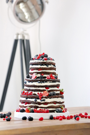 Wedding rustic naked cake with fruits on wooden background