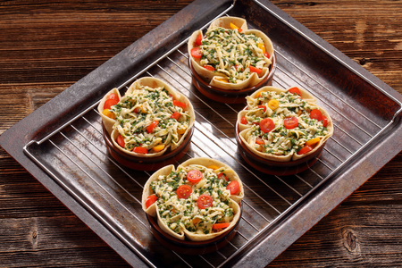 Casserole with cheese, spinach and tomatoes ready for bakingの写真素材