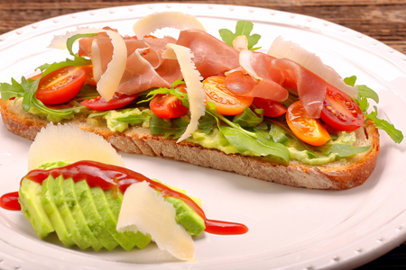 Avocado sandwich on fresh bread with arugula ham tomato and cheese
の写真素材