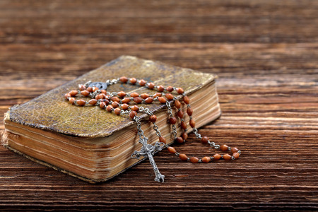 Very old prayer book and vintage rosary on wooden background with empty space for textの写真素材