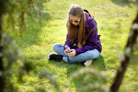 Young girl sitting on the grass with mobile phone

の写真素材