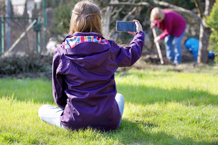 Young girl sitting on the grass and doing photo at the working woman

の写真素材