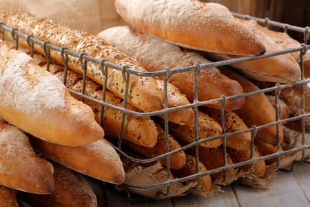 Different types of baguettes in metal basket in bakery