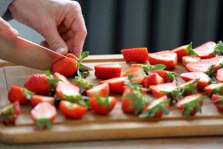Confectioner sliced strawberries for garnishing the cakeの写真素材