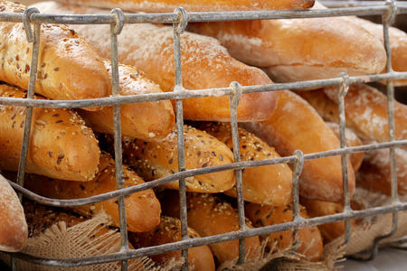 Fresh baguettes in metal basket in bakery