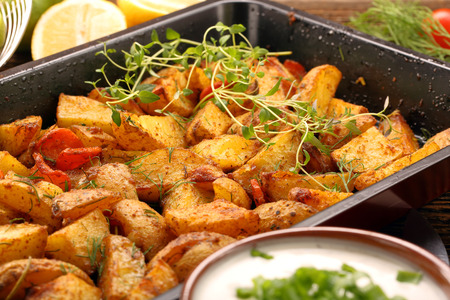 Baked potatoes with herbs on wooden backgroundの写真素材
