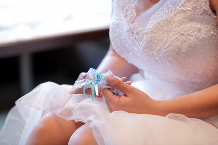 Bride holding beautiful white and blue wedding garterの写真素材