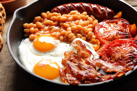 English Breakfast with sausages, grilled tomatoes, egg, bacon and beans on frying pan.
の写真素材