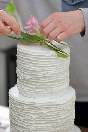 Confectioner decorates white wedding naked cake and empty space for textの写真素材