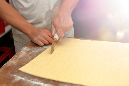 Baker cuts the dough for croissants and empty space for textの写真素材