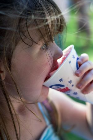 Young brunette girl eating a snow coneの写真素材