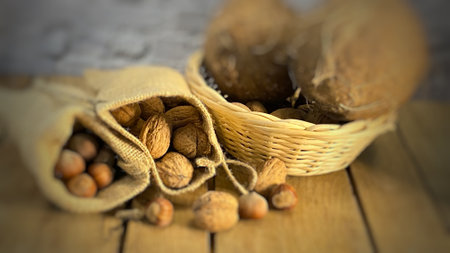 Walnuts and hazelnuts in jute bags and coconuts in a wicker basketの写真素材