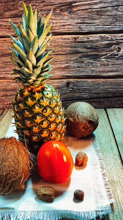 Pineapple on a jute napkin and oak boards, surrounded by coconuts, mangoes and walnuts and hazelnutsの写真素材
