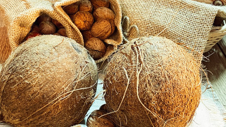 walnuts and hazelnuts in burlap bags coconuts in a wicker basketの写真素材