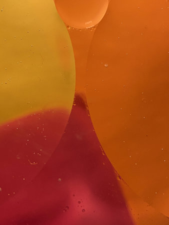 Floating oil drops shimmering in different colors and shapes next to air bubbles on a colored...