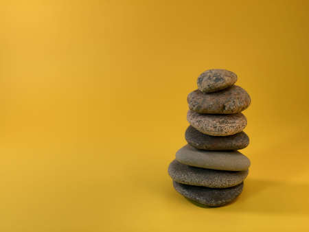 On the yellow background there are pebble stones arranged from the largest to the smallestの写真素材