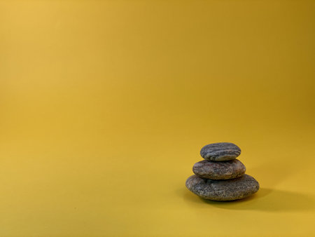 On the yellow background there are pebble stones arranged from the largest to the smallestの写真素材
