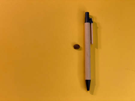 On the yellow background there is a wood pen and a coffee beanの写真素材