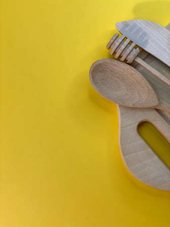 On a yellow background is a cutting board and wooden cutleryの写真素材