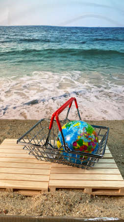 at the seaside, the shopping cart stands on a pallet with a globeの写真素材