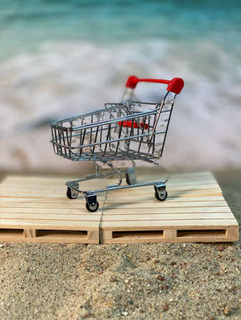 at the seaside, wooden pallets are lying on the sand, there is a supermarket cart on the beachの写真素材