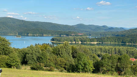 slightly cloudy sky sunny day over Lake Solinie you can see the tops of the Bieszczady Mountains covered with coniferous forestsの写真素材