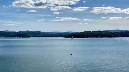 slightly cloudy sky sunny day over Lake Solinie you can see the tops of the Bieszczady Mountains covered with coniferous forestsの写真素材