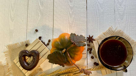 there are cups with coffee on wooden jute napkins the bottoms are gingerbreads everything is lying on a painted wooden tableの写真素材