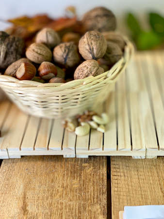 walnuts and hazelnuts lie in a basket on wooden pallets that lie on an oak table, zamiakulkas leaves visible in the background siciana from pine boards painted whiteの写真素材