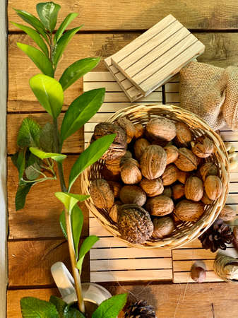 walnuts and hazelnuts lie in a basket on wooden pallets that lie on an oak table, zamiakulkas leaves...