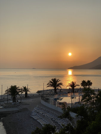 Orange sun reflect their rays in Adriatic sea visible mountains palm treesの写真素材