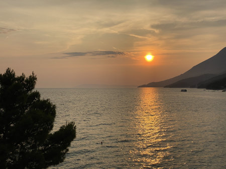 Orange sun reflect their rays in Adriatic sea visible mountainsの写真素材