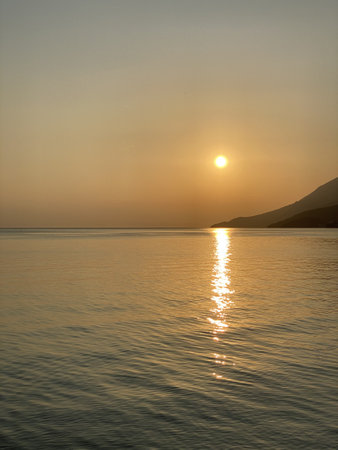 Orange sun reflect their rays in Adriatic sea visible mountains palm treesの写真素材