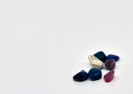 Seven semi-precious gemstones against a white background in the right corner of the photo. They are blue and purple colored. With space to place your text.の写真素材