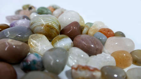 A heap of tumble finished mixture of semi-precious stones on a white background.の写真素材