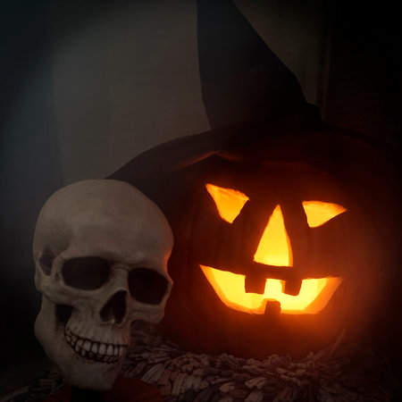 For Halloween: nightmare skull and lighted pumpkin with a witch hat in the fogの写真素材