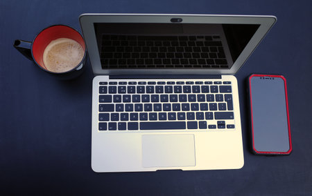 Top view on a working place with laptop, smartphone and black and red mug with coffee