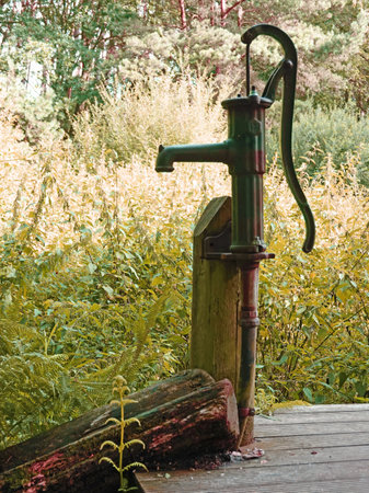 An old-fashioned water pump at a clear stream called Itter in Germanyの写真素材