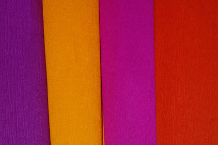 Rolls of crepe paper lying next to each other in the colors purple, red, orange, lilacの写真素材