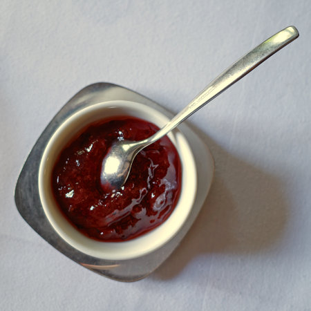 Small bowl with delicious strawberry jam. A spoon and a steel dish. Part of the breakfast tableの写真素材