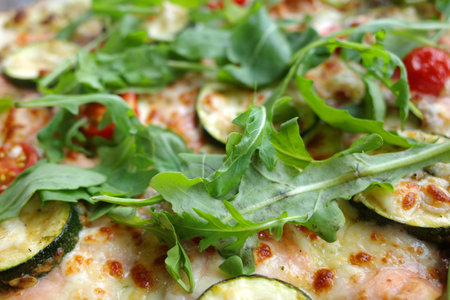Delicious pizza with tomatoes, arugula leaves, zucchini and salmonの写真素材