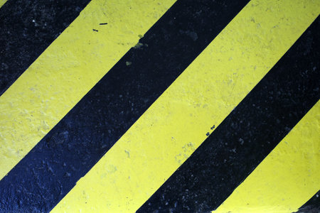 Detail of a yellow, black painted threshold with diagonal lines. Intended as yellow black grunge backgroundの写真素材