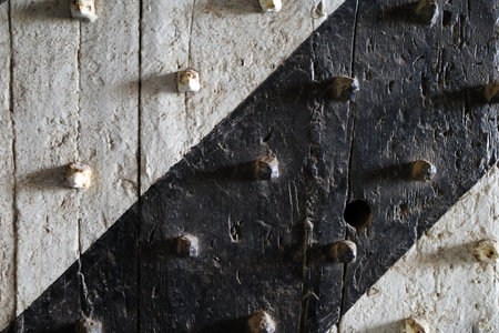 Detail of a white, black painted fortified centuries-old fortress door with diagonal lines and...