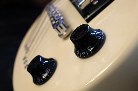 Close-up of the volume and tone controls on a white electric guitar